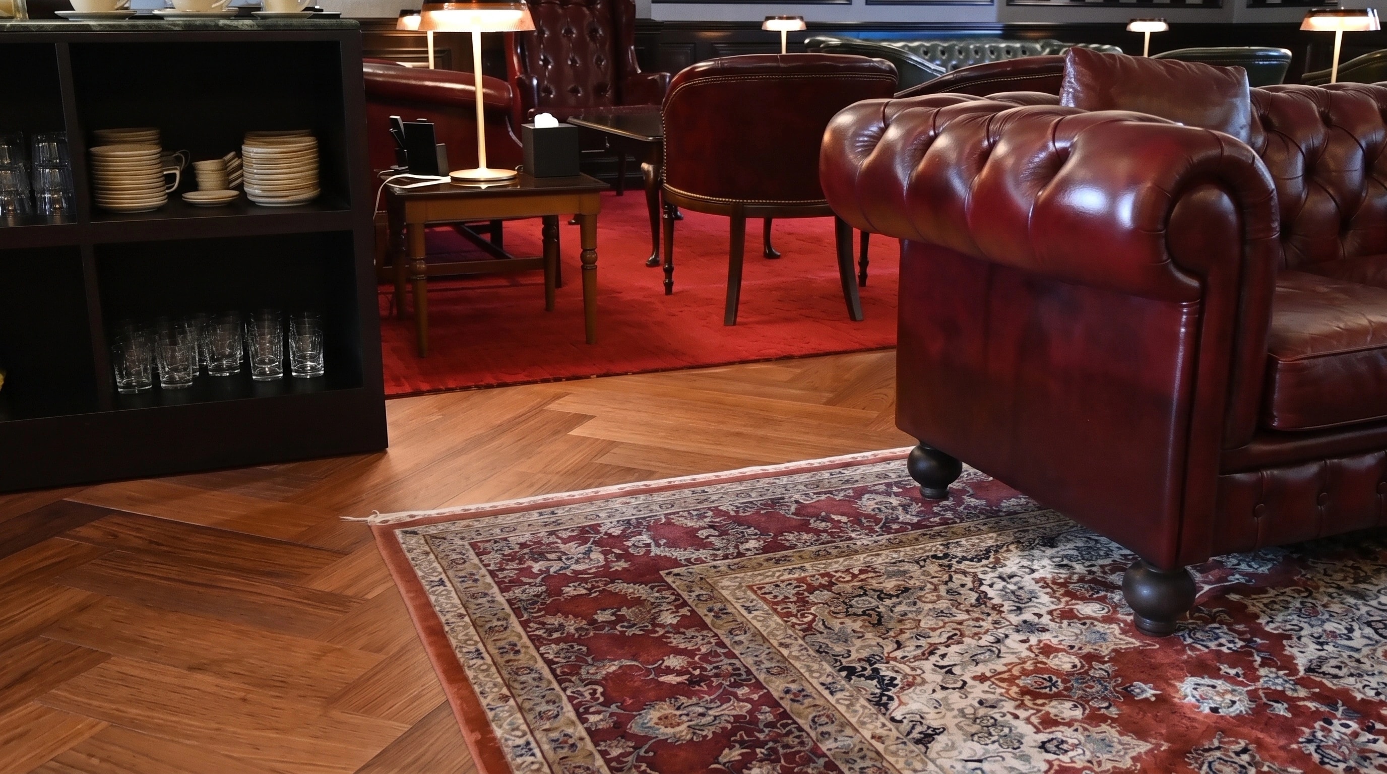 Chevron parquet running beneath a patterned rug in an executive lounge