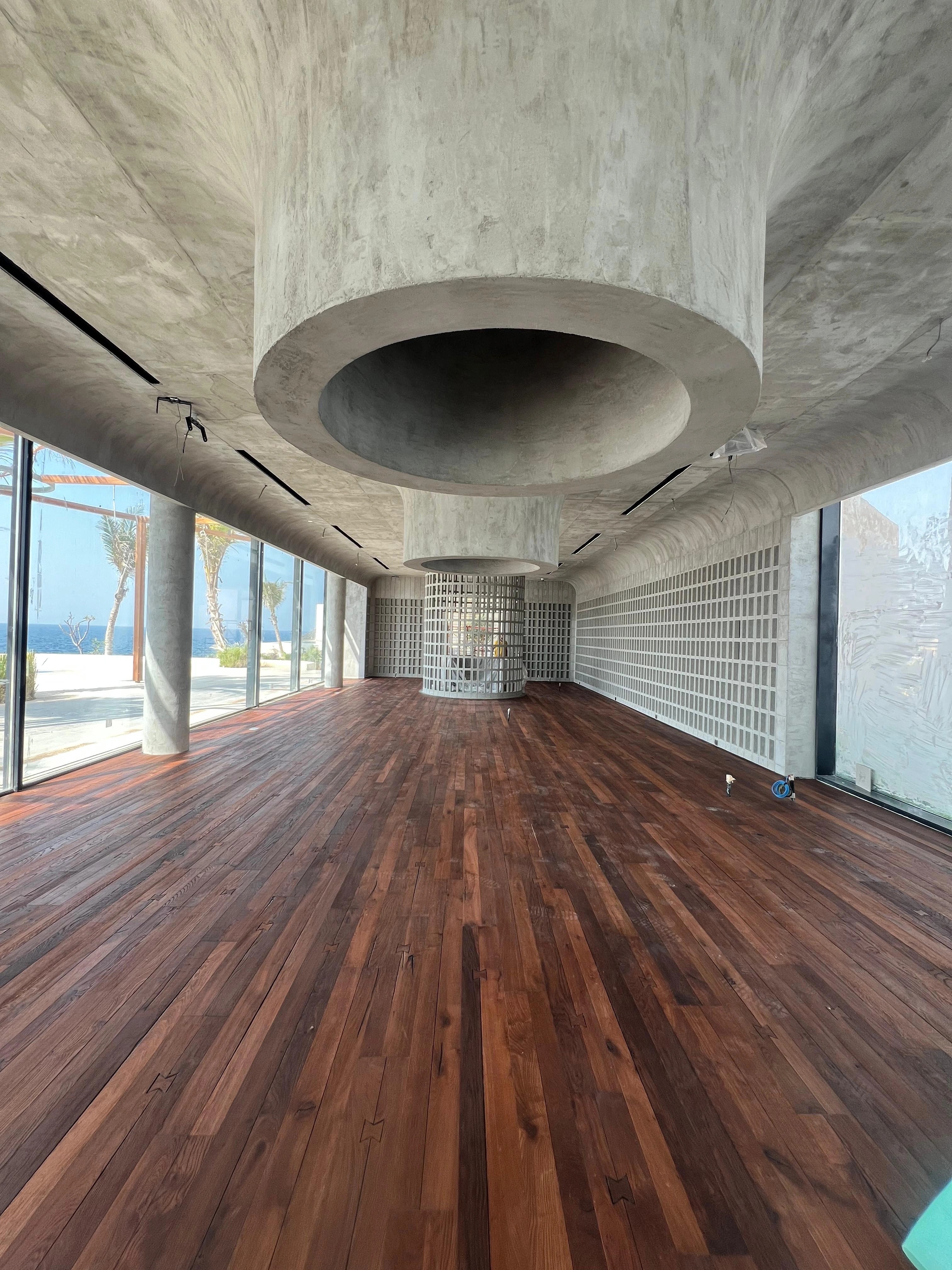 Dark timber flooring completed beneath a circular concrete ceiling